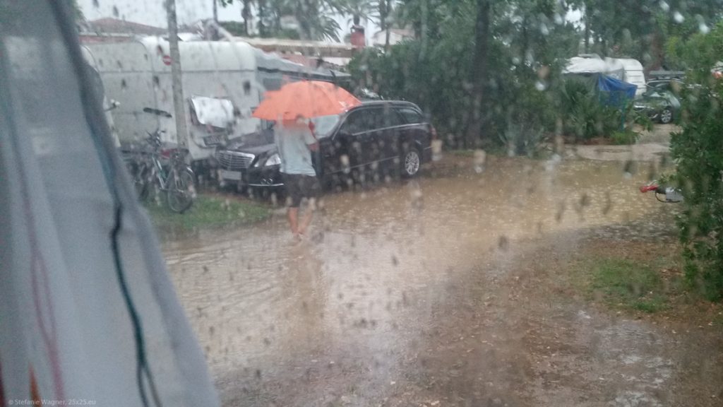 View out of the trailer window, the street covered with ankle deep water and a man walking through it.