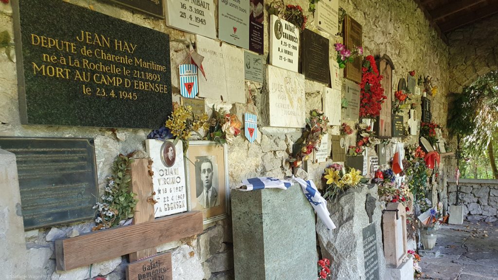 A wall with commemorative plaques having names, pictures and additional texts on them