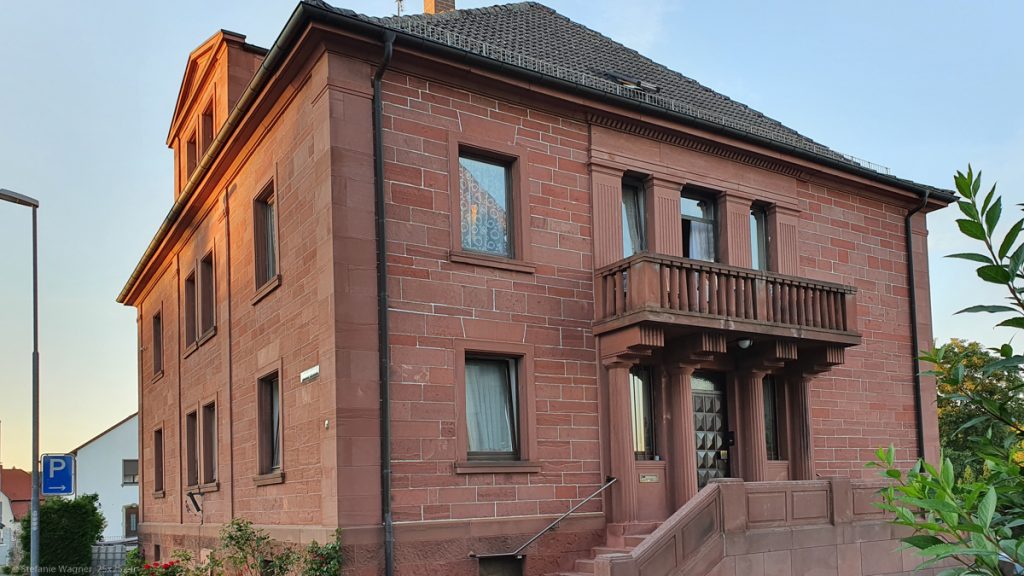 A square house with two floors made out of red sandstone