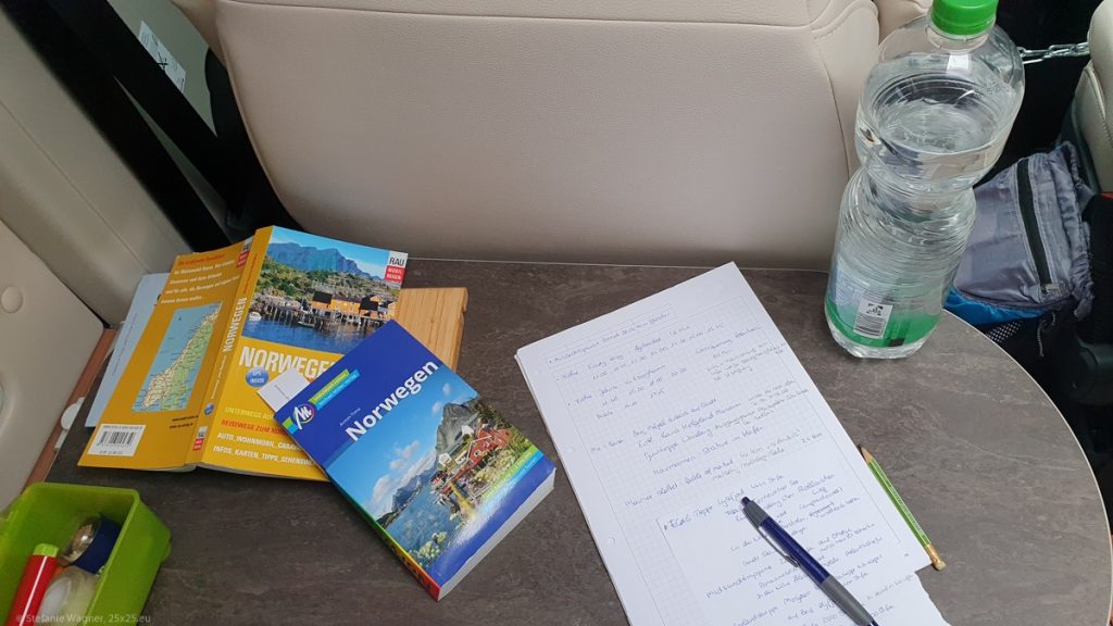 Two travel guides, sheets of paper, and pen on a desk