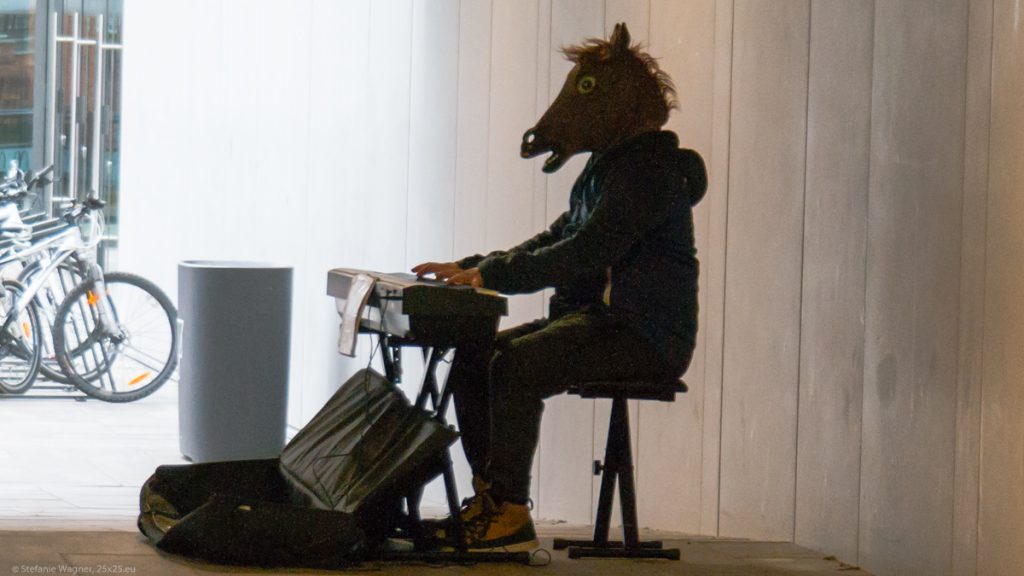 Musician wearing a horse mask playing a piano