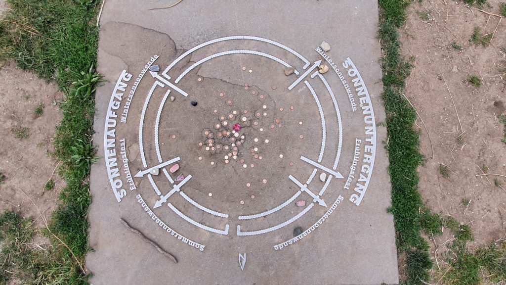 A concrete board on the ground with metal application. Showing the circles of the observatory and the gates with descriptions.