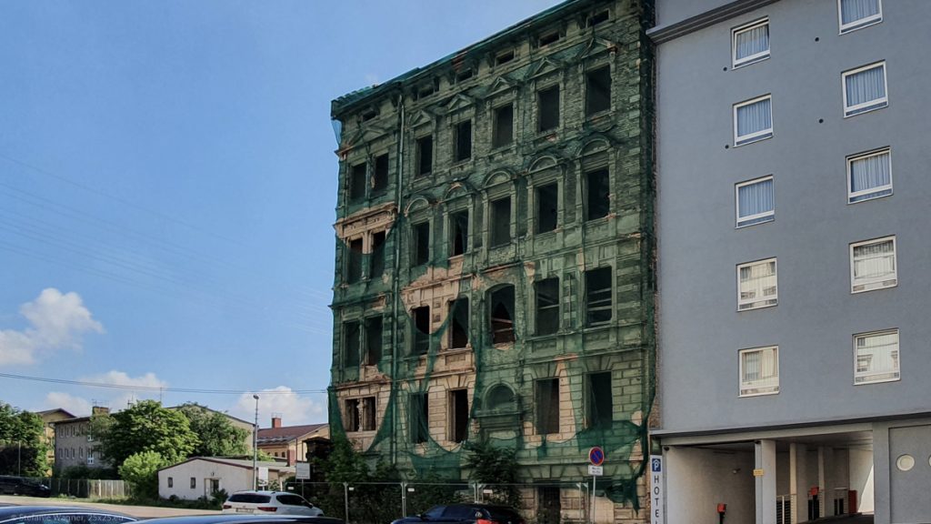 Old facade covered with a green net that has already big holes in it
