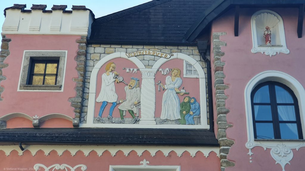 Details of the pink building, showing a dentist with a huge drill and teeth hanging over some bar