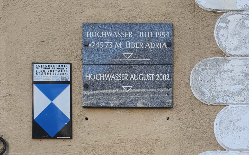 2 plates saying "Hochwasser Juli 1954, 245,73 M über Adria" and "Hochwasser August 2002" below.