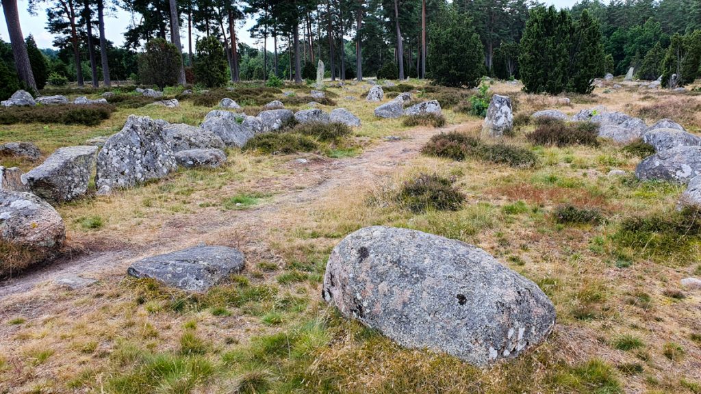 Gray stones in the grass, a small dirt trail running through them from lower left to upper right