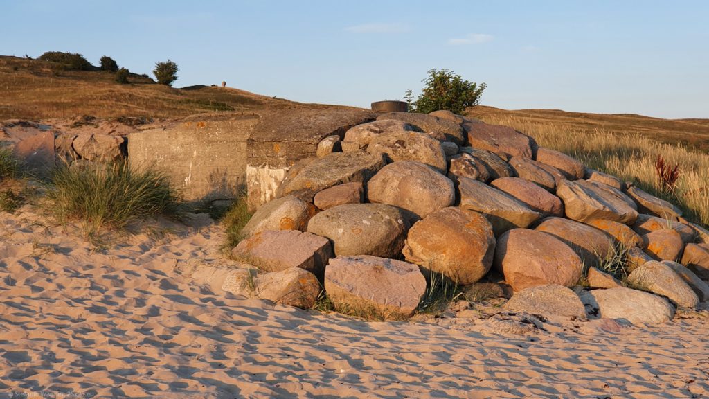 Part of a concrete bunker in the back, big stones piled up in its front