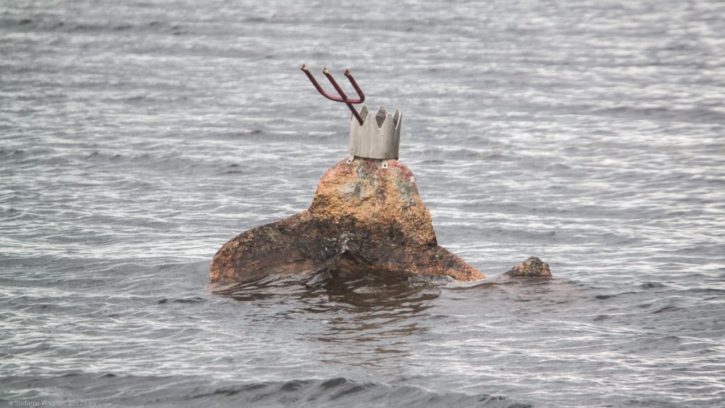 Stone in the water with a metall crown and a trident