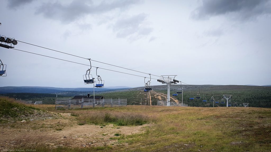 Ski lift with blue seats above brownish gras, gray sky
