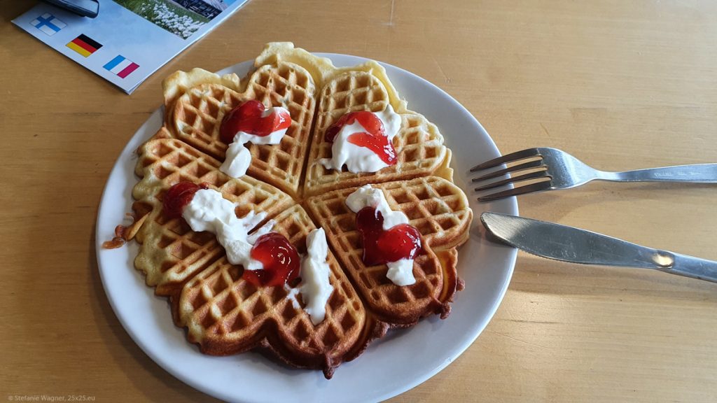 Waffle (heart shaped pieces) on a plate with sour creme and red marmalade on the sour creme.