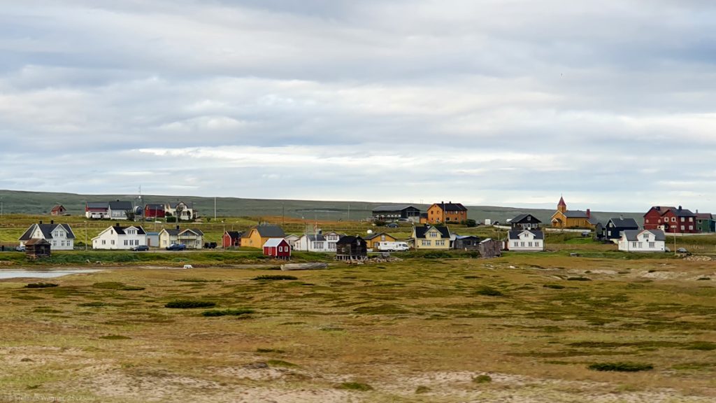 Several colored houses scattered around, brouwn-greenish emtpy landscape, mostly flat