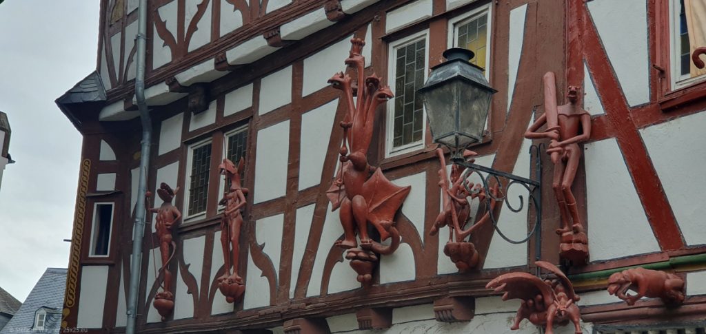 A half-timbered house with red figures that resemble dragons.