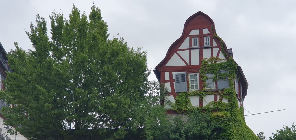 Small, half-timbered house withonly two windows on one floor. The left window is visibly tilted.