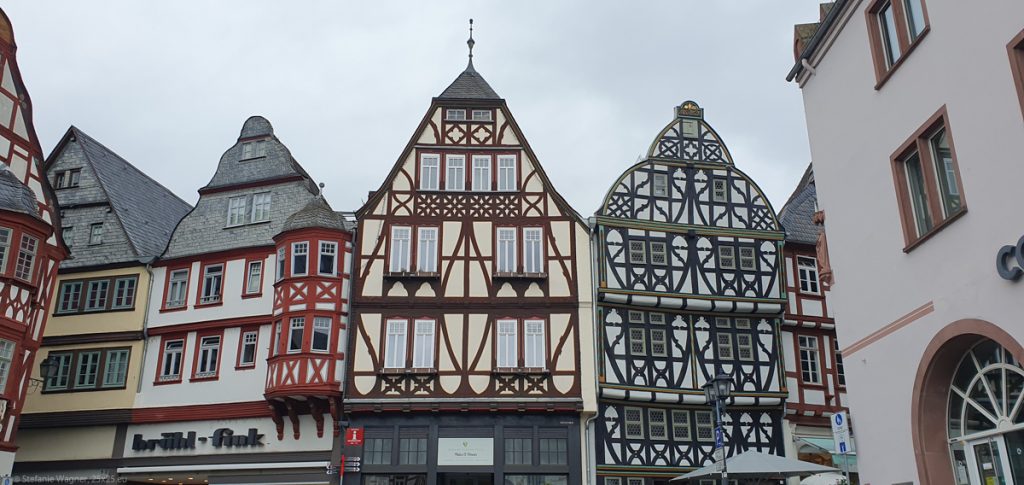 Several half-timbered houses. The beams are in red, brown and green and very ornamental.